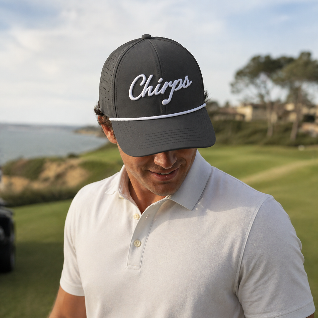 Chirps Performance Rope Hat in charcoal gray, worn on a coastal golf course